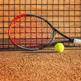 Rakieta tenisowa Wilson Clash i piłka leżą na korcie, gotowe do gry.