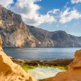 Acantilados dorados y mar azul en Ibiza, un rincón que evoca la magia de Atlantis Ibiza.