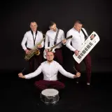 Zespół muzyczny grupa speed: saksofonista, gitarzysta, klawiszowiec i perkusista w białych koszulach i bordowych spodniach w kratę.