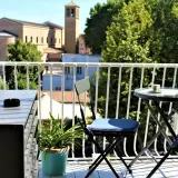Idealne miejsce, gdzie nocować w Rzymie: balkon z widokiem na kościół i drzewa, stolik z kawą czeka.