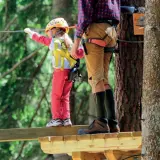 Un bambino e un adulto su un percorso avventura. Un perfetto weekend con bambini nel Nord Italia, tra alberi e adrenalina.