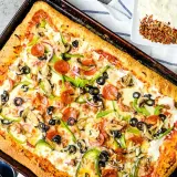 Pyszny przepis na pizzę z serem, pepperoni, pieczarkami, papryką i oliwkami. Idealna na rodzinny obiad.