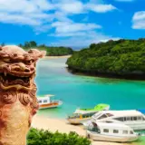 Kamienna lwica strzeże rajskiej plaży z łodziami na turkusowej wodzie. To piękny archipelag z Okinawą w tle.