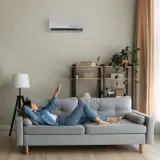 Soggiorno con pareti grigio moderno, divano comodo e aria condizionata. Perfetto per rilassarsi con un libro.