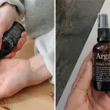 En hand applicerar arganolja för hudvård. Flaskan med ekologisk kallpressad arganolja syns också.
