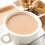 Aromaticzne cafe au lait w białej filiżance, obok ciasteczka z kawałkami czekolady. Idealny poranek.