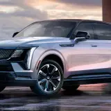 Elegancki Cadillac Escalade 2025 w kolorze srebrnym, z czarnym dachem i stylowymi felgami, prezentuje się imponująco na mokrej nawierzchni.