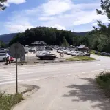Duży parking na przełęczy wyżniańskiej, pełen samochodów podziwiających górskie krajobrazy.