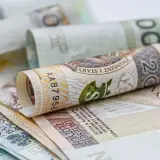 Zwijane polskie banknoty, w tym 20 złotych, symbolizują oszczędności na dodatkowy urlop.