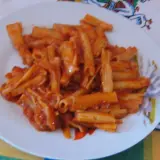 Pyszny makaron z sosem pomidorowym na białym talerzu, gotowy do zjedzenia.