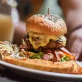 Ogromny burger z rozpływającym się serem, chrupiącym boczkiem i surówką. Wygląda jak posiłek dla prawdziwego drwala!