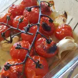 Tomates cerises au four, caramélisées et parfumées à l'ail, dans un plat en verre.