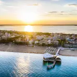 Coucher de soleil sur Lignano, Italie. La plage et la mer s'étendent à perte de vue, avec un pont moderne se jetant dans l'eau.