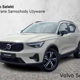 Jasny beżowy Volvo XC40, używane z salonu, prezentuje się elegancko na tle betonowej ściany.