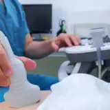 Lekarz wykonuje badanie USG, aby zbadać trzustkę pacjenta. Aparatura i sonda są widoczne.