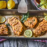 Vier goldbraune Schnitzel im Backofen, garniert mit Petersilie und Zitronenscheiben. Ein Genuss für Augen und Gaumen!