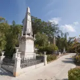 Un obelisco y monumentos se alzan en el cementerio de los ingleses, un lugar sereno bajo un cielo azul.