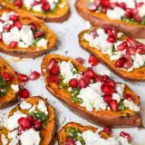 Pieczone bataty z piekarnika, udekorowane zielonym pesto, fetą i pestkami granatu. Pyszna przekąska!