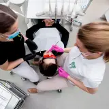 Dwie asystentki stomatologiczne pracują przy pacjencie. Zastanawiasz się, ile zarabia asystentka stomatologiczna?