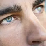 Primer plano de los ojos de un hombre, destacando sus cejas pobladas y el iris azul verdoso.