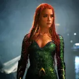 Amber Heard w zielonym kostiumie z filmu "Aquaman". Jej długie, rude włosy opadają na ramiona.