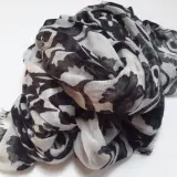 Ein leicht zerknitterter Schal aus Polyester-Plastik mit einem auffälligen schwarz-weißen Blumenmuster.