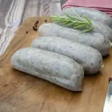 Saucisses grises sur planche en bois, avec romarin et poivre. La différence entre andouille et andouillette est subtile, mais la texture ici suggère une andouillette.