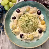 Un délicieux poulet au raisin crémeux, servi avec du riz et garni de persil frais. Des grappes de raisins noirs et verts complètent cette assiette appétissante.