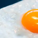 Un œuf au plat, avec son jaune d'or brillant, est servi dans une assiette bleue. Les **œufs frits** sont un délice simple.