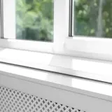 Biały parapet zewnętrzny z widocznym uszczelnieniem, chroniący przed warunkami atmosferycznymi.