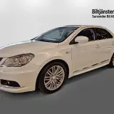 Vit Suzuki Kizashi, en elegant sedan med sportiga fälgar och kromdetaljer.