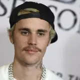 Justin Bieber w czapce z daszkiem i z wąsami, wygląda jakby świętował swoje urodziny.