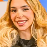 Uśmiechnięta młoda kobieta z blond włosami i piegami.