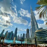 Widok na drapacze chmur w Dubaju, gdzie jest Burj Khalifa, z palmami i błękitnym niebem.