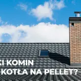 Ceglany komin do kotła na pellet na tle błękitnego nieba z chmurami.