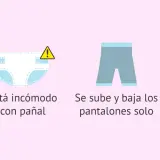 Bebé con pañal limpio, incómodo, bajándose pantalones y curioso por el baño. Señales para quitar el pañal.