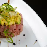 Deliziosa tartare di tonno con avocado e ananas, guarnita con erba cipollina e semi di sesamo nero.