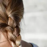 Närbild på en fläta med blont hår. Några små hårstrån som går av syns längs med flätan.