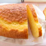 Un soffice plumcake allo yogurt, dorato e invitante, tagliato a fette su carta bianca.