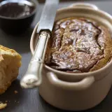 Un délicieux gâteau de foie de volaille à l'ancienne, servi avec du pain croustillant et une petite coupelle de confiture.