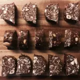 Chokladiga egna bars med nötter och kokos, upplagda på en träskärbräda.