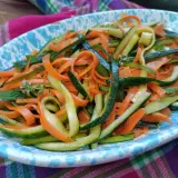 Deliziosa insalata di zucchine e carote a julienne, guarnita con menta fresca. Un piatto leggero e colorato.