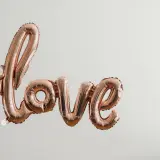 Różowe balony w kształcie napisu "love" unoszą się w powietrzu, tworząc piękną definicję miłości.