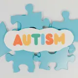 Niebieskie puzzle układanki otaczają chmurkę z napisem AUTYZM. Każdy element to unikalny fragment, jak w spektrum autyzmu i aspergerze.