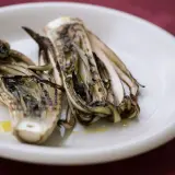 Radicchio grigliato in friggitrice ad aria, servito su un piatto bianco con un filo d'olio.