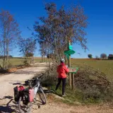 Ciclista consulta señalización en la **vía verde del Tajuña**. Bicicleta con alforjas lista para la aventura.