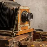 Antyczny aparat mieszkowy na kufrach. Zastanawiasz się, w którym roku wynaleziono aparat fotograficzny?