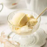 Copa de cristal con helado de mantecado cremoso, servido con una cuchara dorada.