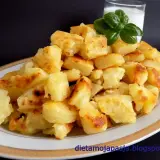 Usmażone ziemniaki na talerzu, obok szklanka mleka i listek bazylii.