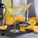 Dwa kieliszki z martini, cytryny i shaker. Idealne na orzeźwiający drink.